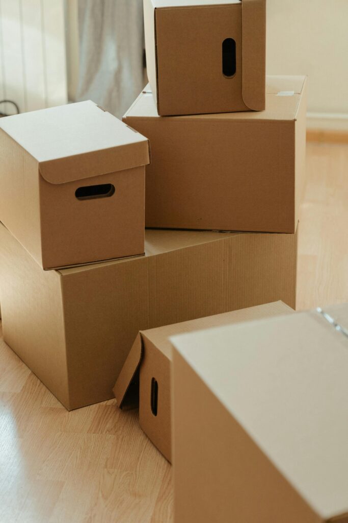 Cardboard boxes stacked on a wooden floor, symbolizing moving and new beginnings.