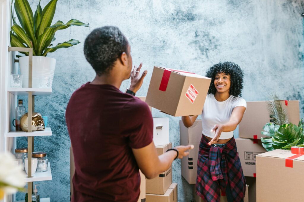 Couple joyfully handling moving boxes while relocating to a new home.